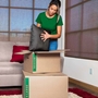 woman packing black pillow into medium moving box