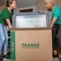 two women placing bubble wrapped frame into a frame moving box